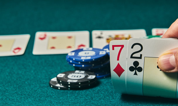 Bad poker gamble or unlucky hand concept with player going all in with 2 and 7 (two and seven) offsuit also called unsuited, considered the worst hand in poker preflop (before the flop is revealed)