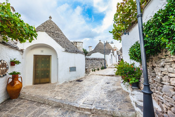 Beautiful town of Alberobello with Trulli houses among green plants and flowers, Apulia region,...