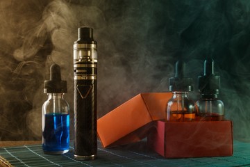 Electronic cigarette and bottles with vape liquids, two of them into opened gift box, surrounded by...