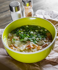 Chicken soup with green onion and croutons in bowl on wooden table