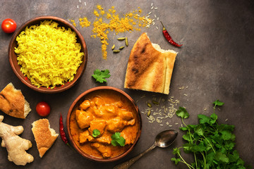 Chicken tikka masala spicy curry meat food , rice and naan bread on a brown rustic background. Indian and UK dish. Top view, copy space, flat lay.