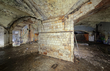 A wide column of an abandoned building lined with white tiles covered with dirt, cracks and smudges.