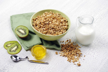 Granola with kiwi, nuts and milk on a bright table.
