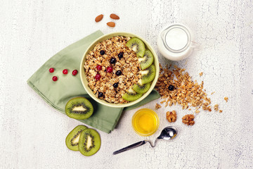 Granola with kiwi, nuts and milk on a bright table.