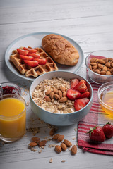 Breakfast: sweet delicious oatmeal, waffle with berry. Croissant, almond, orange juice on white table