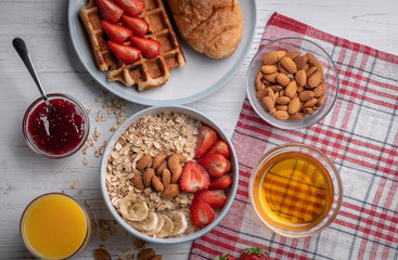 Oatmeal. Breakfast. Food. Muesli. Snack. Morning meal. Fresh waffles. Strawberry, honey, jam, almond and croissant on white table