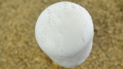 View from the top of a beer in a foam glass made from hops in a craft brewery against the background of healthy malt and barley grains