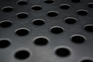 Gray monophonic background with big quantity of holes in a metal plate. Surface. Texture.