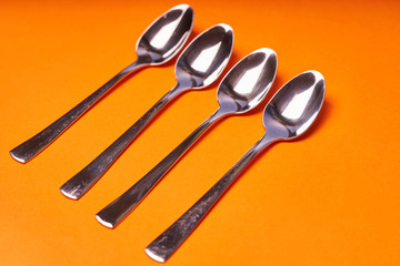 four teaspoons laid out on an orange background