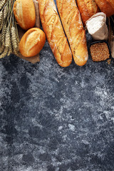 Assortment of baked bread and bread rolls on rustic grey bakery table background