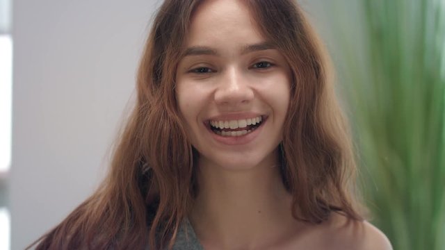 Portrait smiling woman licking tongue to white teeth front mirror in bathroom