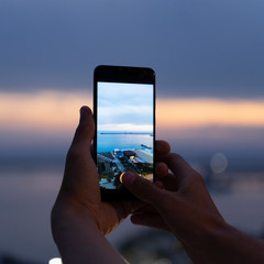Man taking photos of sunset with mobile phone. Tourist is shooting video and photo of beautiful...