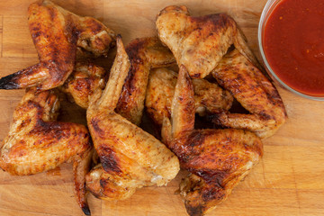 Chicken wings with red sauce on wooden background.