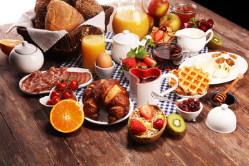 Fototapeta na wymiar Huge healthy breakfast on table with coffee, orange juice, fruits, waffles and croissants. Good morning concept.