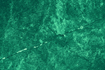 Vintage green background. Rough painted wall of emerald color. Imperfect plane of virid colored. Uneven old decorative toned backdrop of green tint. Texture of emerald hue. Ornamental stony surface.