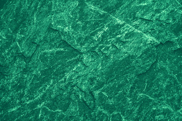 Vintage green background. Rough painted wall of emerald color. Imperfect plane of virid colored. Uneven old decorative toned backdrop of green tint. Texture of emerald hue. Ornamental stony surface.