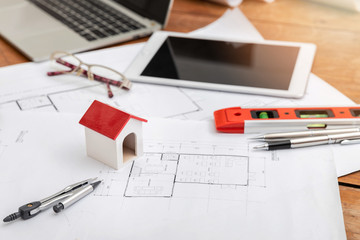 Business, architecture, building and construction concept - A architects house model with measurement tool and blueprints on architect desk.