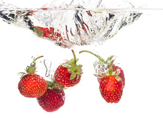 Red fresh strawberries thrown into the water, under water. Spat and splash