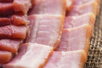  Fresh cooked food. Fresh cold sliced bacon on the background of natural linen fabric. Raw chopped bacon for cooking. Bacon slices close-up.