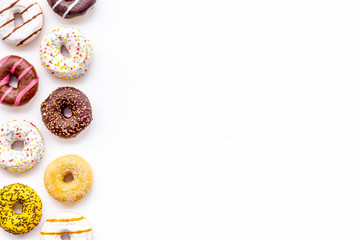 Donuts of different flavors for breakfast on white background top view