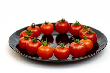 Tomatoes in a black plate isolated on white background. Composition of red tomatoes on a white background. Place for text