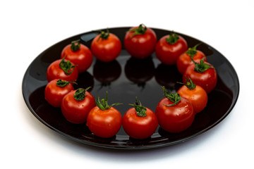 Tomatoes in a black plate isolated on white background. Composition of red tomatoes on a white background. Place for text