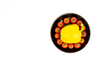 Yellow sweet pepper with tomatoes in a black plate isolated on white background. Composition of yellow peppers and red tomatoes on a white background.