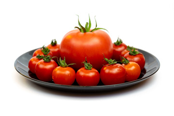 Tomatoes in a black plate isolated on white background. Composition of red tomatoes on a white background. Place for text