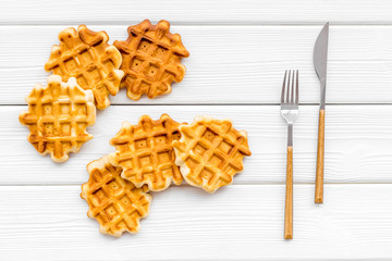 homemade Belgian waffles on served table on white wooden background top view