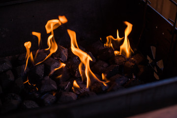 Hot coals in the fire.burning coals in the barbecue, fire in the grill.charcoal preparing for grilling, barbecue grill.Flames and coals of a fire burning at night . Background of hot coals.