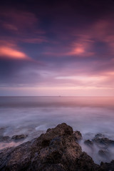 Fototapeta premium sunset are on the coast with rocks in the foreground vertical
