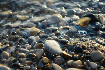 pebble stones on the sea beach, the rolling waves of the sea with foam