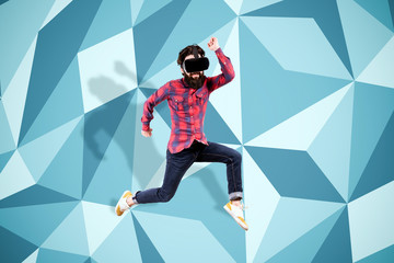 full length portrait of young bearded hipster man in virtual reality glasses, jumping over colored background