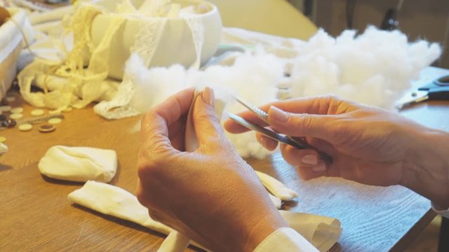 Making of handmade doll. Woman stuffing doll details with synthetic winterizer.