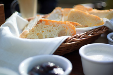 Fototapeta na wymiar Close up of the basket with freshly baked bread on the table near jam. Breakfast concept
