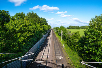 Bahn Gleise, Schienen führen gerade zum Horizont bei blauem Himmel durch grüne Natur