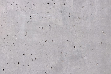 Graue Betonwand, Steinwand mit leichten Strukturen und löchern über das ganze Bild verteilt. Grauer Hintergrund mit feinen grauen Nuancen. Industrial Design Hintergrund, Textur , gestalterisches Eleme