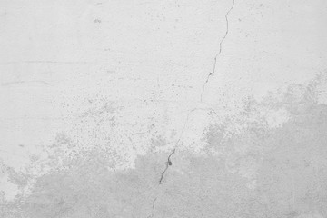 Grauer Hintergrund einer Betonwand mit einem Riss Quer durch das Bild. Mittelgrauer Verlauf und verputzte Stellen im unteren Bild. Texturierte Wand im Industrie Style. 