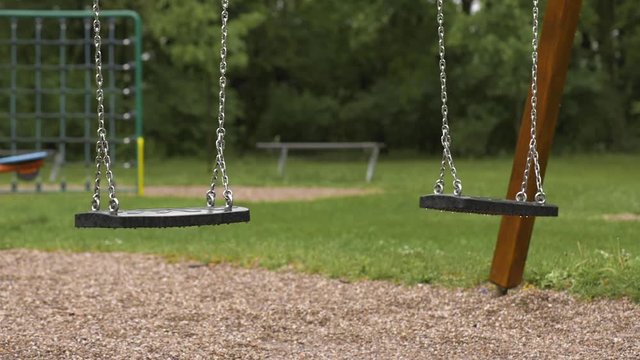 Empty playground after rain. Swing got wet in raindrops. Summer or spring rainy day. No people. No children.