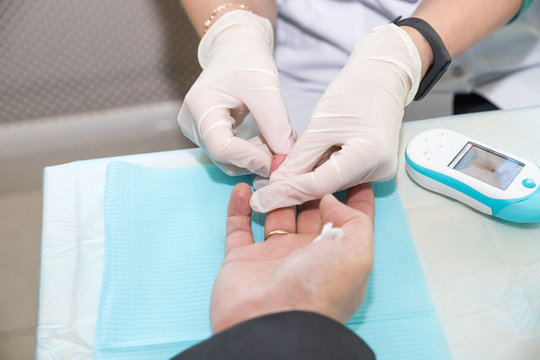 Doctor Taking Blood Sample from Boy's Finger. Diabetes Concept. Sugar in Blood. Healthcare Concept. Young Man in Uniform. White Coat. Medical Equipment. Boy in Clinic. Glucometer in Hand.