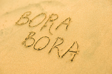 Word Bora-Bora written on the sand beach in summer on vacation inspire to travel.  Romantic travel for love couples or family holidays. resort islands for tourists. Relaxing sign on sand