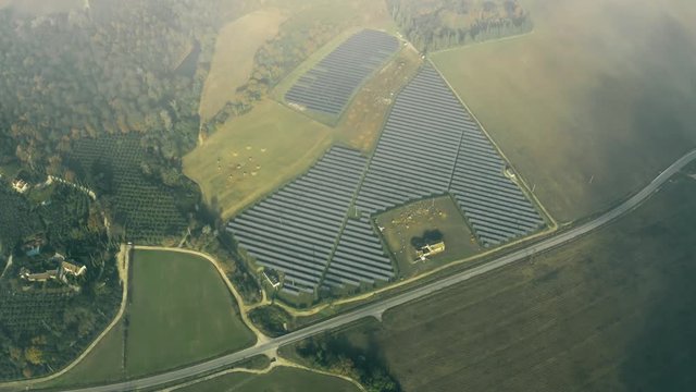 Aerial view of a solar power station and a sheep farm below clouds. Umbria, Italy