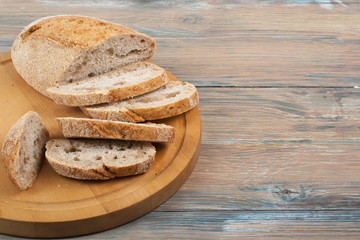 Many mixed breads and rolls of baked bread on wooden table background.