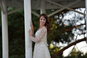 Naklejka premium A woman in a white dress in the park at the gazebo