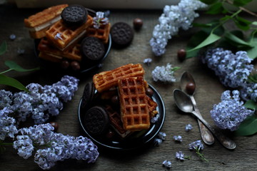 Viennese waffles and lilacs on dark wooden background