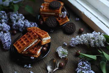 Viennese waffles and lilacs on dark wooden background