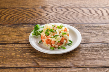 Potato salad with smoked salmon and green onion isolated on wooden background