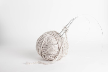 beige yarn ball with woolen thread and knitting needles