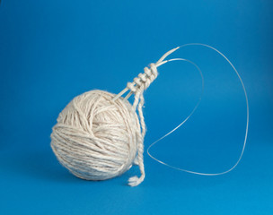 beige yarn ball with woolen thread and knitting needles
