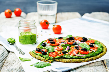 vegan broccoli zucchini pizza crust with spinach pesto, tomatoes, onion and olives